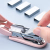 A hand is operating a pink compact mini stapler kit, demonstrating the stapling of small items.
