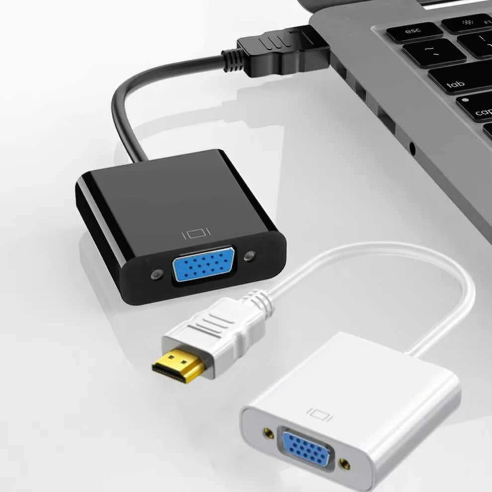 An HDMI to VGA adapter cable with a black box, a white adapter, and a gray laptop keyboard.
