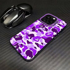 Funda para teléfono de leopardo morado y verde junto a un ratón inalámbrico negro sobre una superficie oscura.