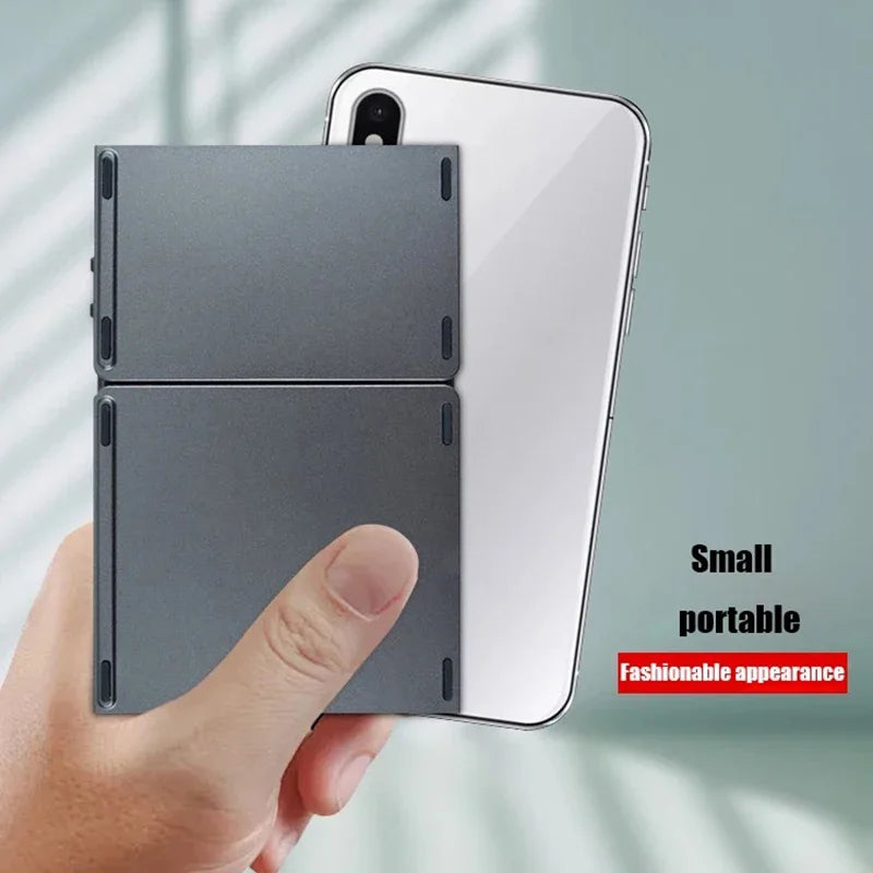 A hand holds a folding Bluetooth keyboard with a touchpad attached to a smartphone.