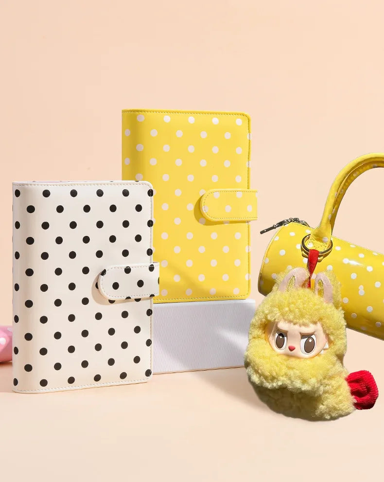 A set of yellow and white polka dot reusable PU leather binders and a fluffy yellow charm.