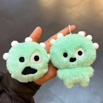 A hand holds a light green plush toy resembling a cute creature with large eyes and small ears.