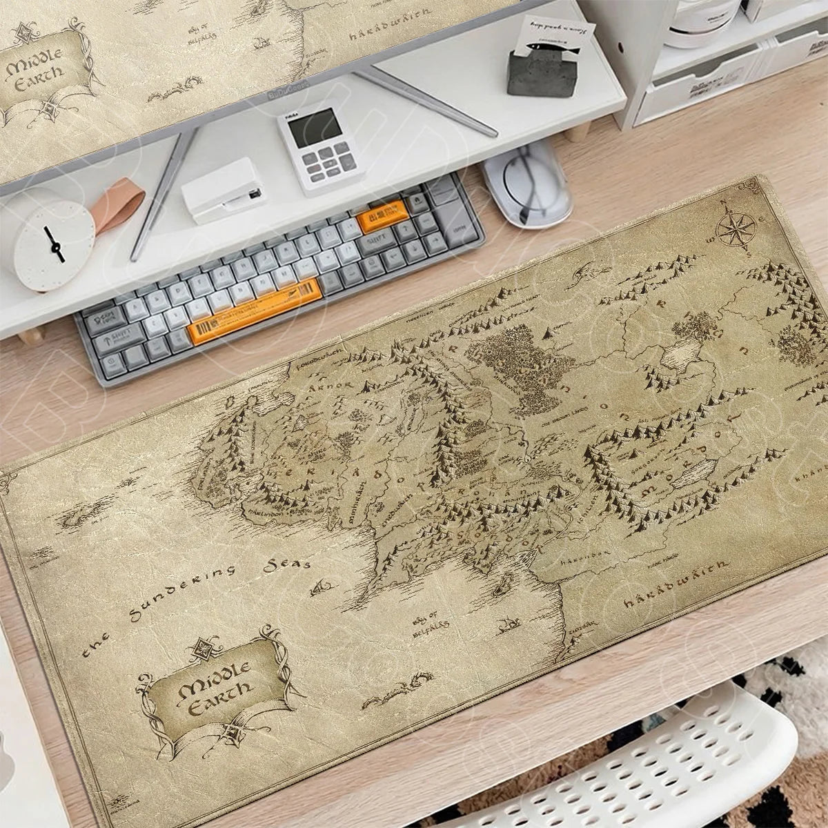 A large beige map of the Middle Earth region is displayed on a desk mat next to a keyboard and mouse.
