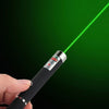 A hand holds an interactive pet training pen emitting a green laser beam against a dark background.
