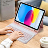 Eine Person tippt auf einem rosa Laptop mit kabellosem Tastatur- und Maus-Set neben einem Buch.