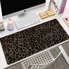 A dark brown leopard print non-slip gaming mouse pad is displayed on a white desk next to a computer monitor and keyboard.