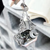 A silver diamond butterfly watch strap is displayed hanging from a chain, with the watch visible below.