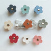 A collection of reusable leather flower cable organizers in various muted colors and shades.