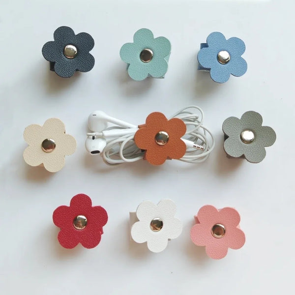 A collection of reusable leather flower cable organizers in various muted colors and shades.