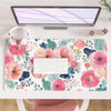 A large pink floral desk mat featuring various flowers and leaves, placed under a laptop and keyboard.