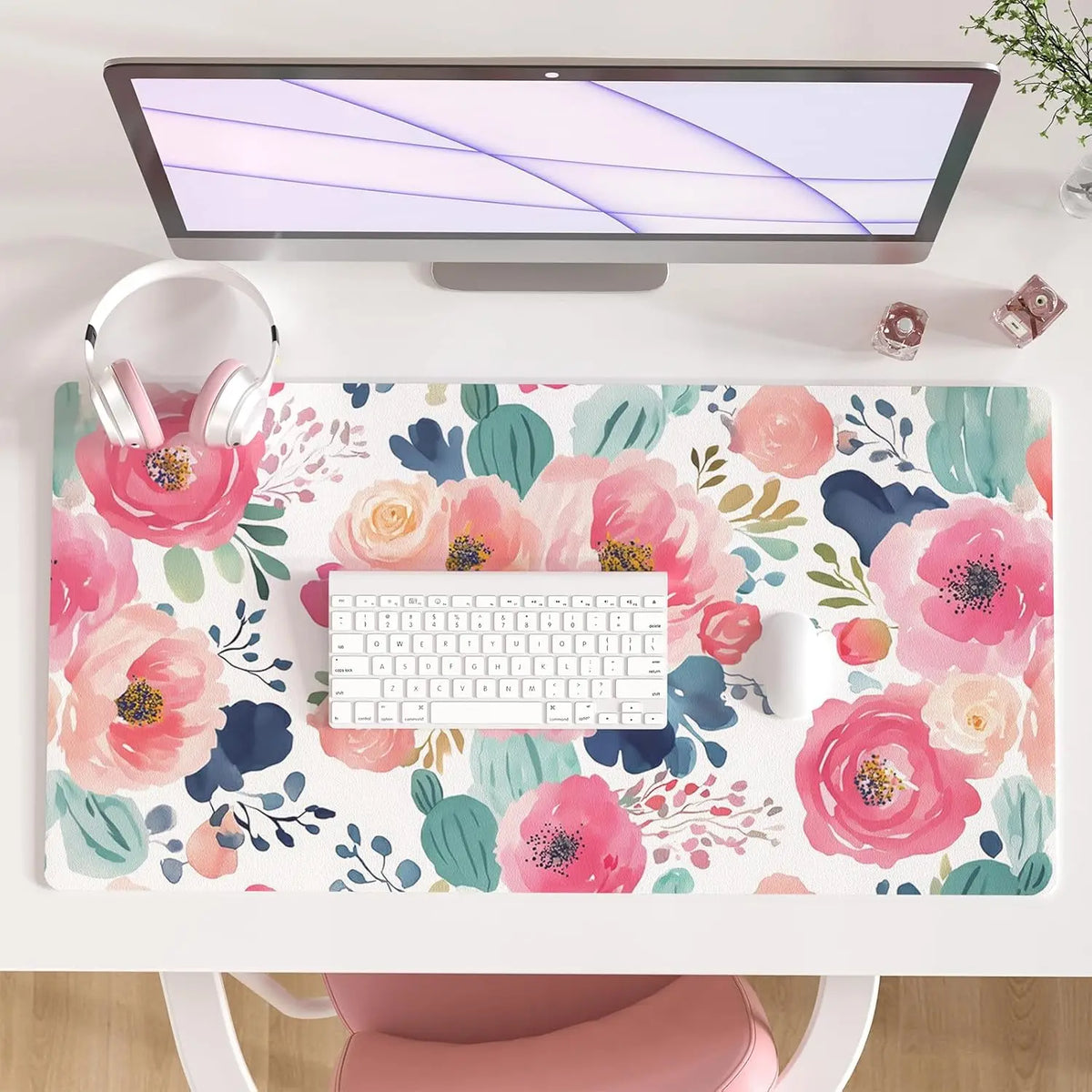 A large pink floral desk mat featuring various flowers and leaves, placed under a laptop and keyboard.