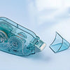 A clear plastic double-sided adhesive tape is shown angled against a light blue background.