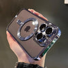 A hand holds a clear magnetic case with a plated finish for a MagSafe iPhone, showing the camera module and Apple logo.