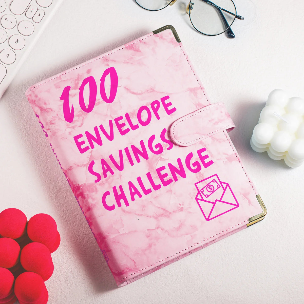 A pink marble budget binder with cash envelopes is shown on a white surface.