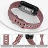 A pink silicone replacement strap for a Fitbit Inspire series watch shown with various components.