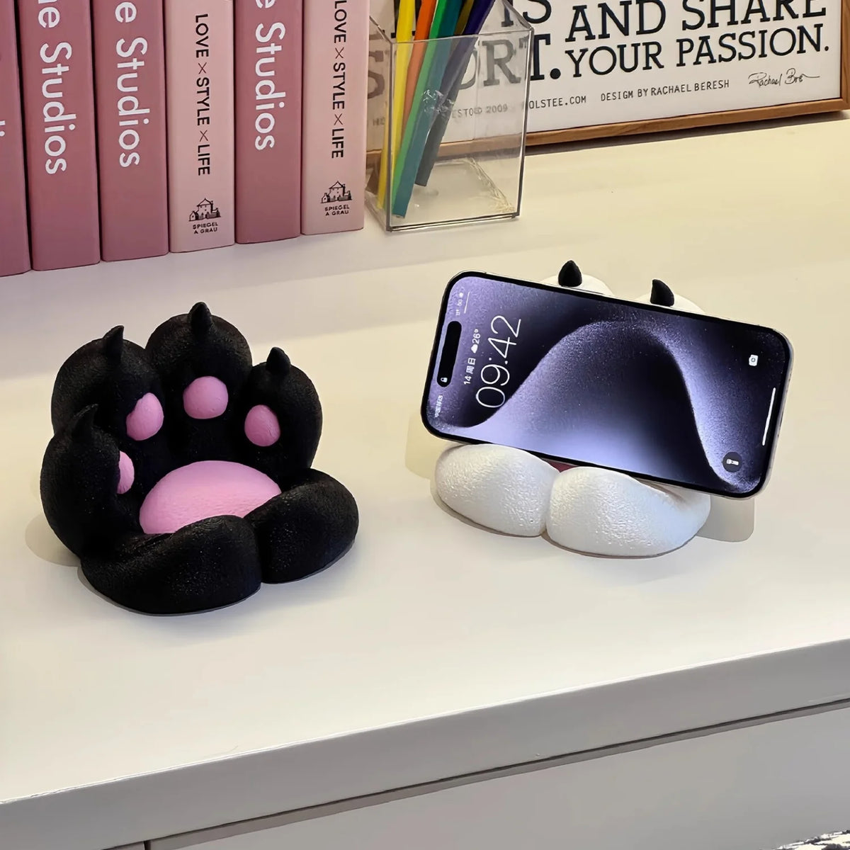 A purple smartphone is displayed on a white stand with a silicone base, next to a black 3D printed cat paw accessory.