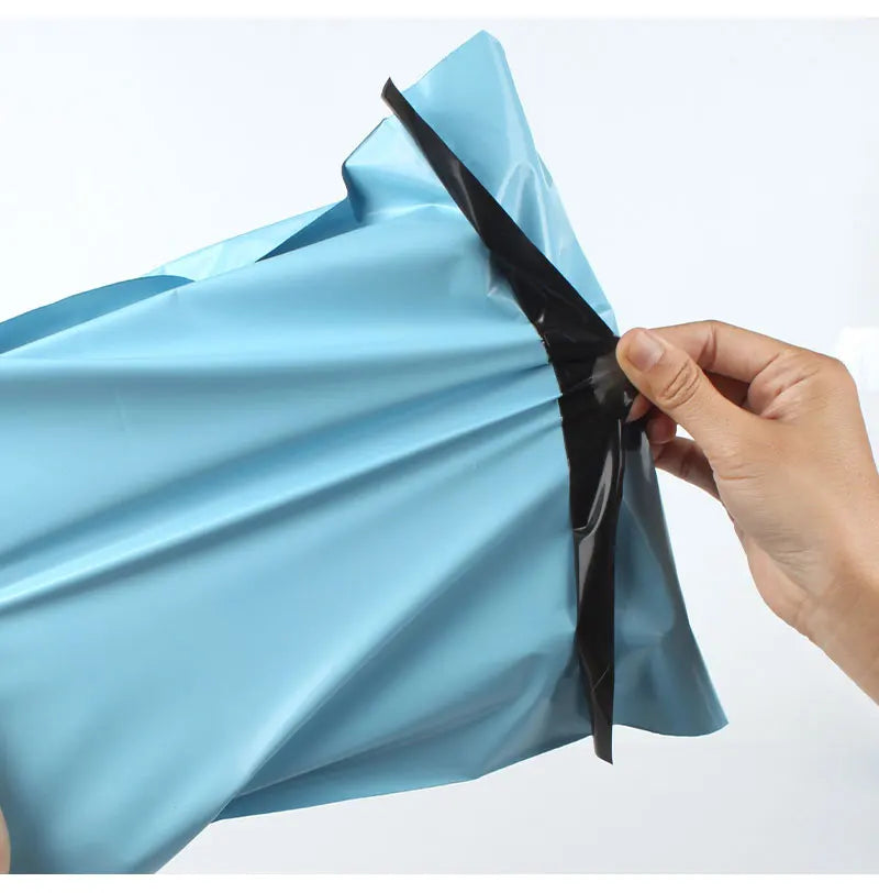 A hand is opening a light blue reusable waterproof poly shipping bag, showing the black sealing strip.