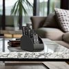 A black remote control holder and desk organizer tray with multiple remotes resting on a marble table in a modern living room