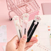 A hand holds three pink and black portable pet claw tools for crafting and decoration on a white surface.