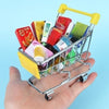 A hand holds a silver shopping cart filled with various colorful stationery and desk supplies.