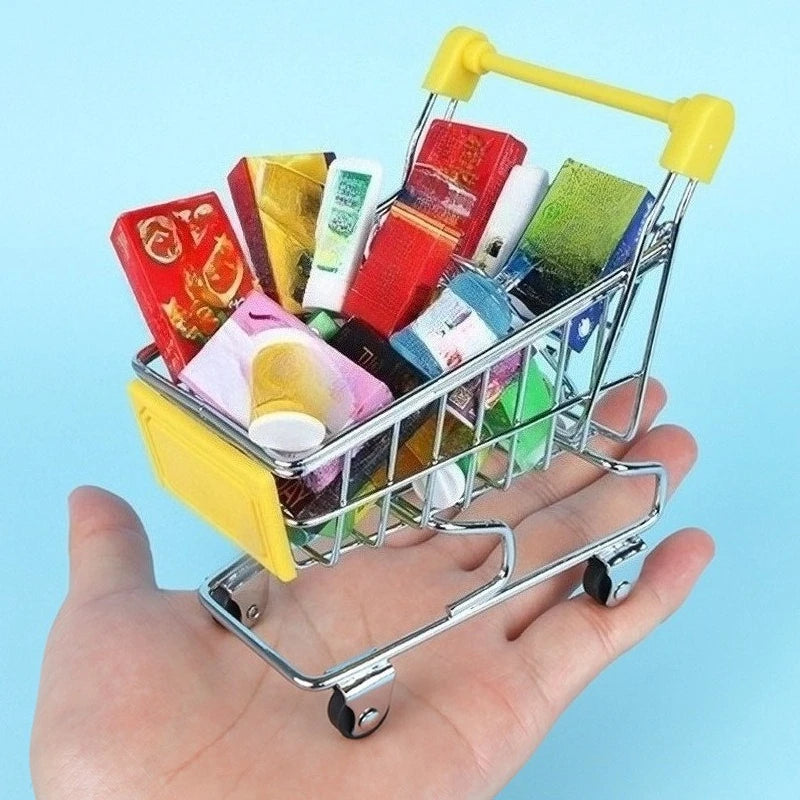 A hand holds a silver shopping cart filled with various colorful stationery and desk supplies.