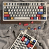 A close-up view of a white mechanical keyboard with colorful comic style keycaps and various keycaps scattered around it on a