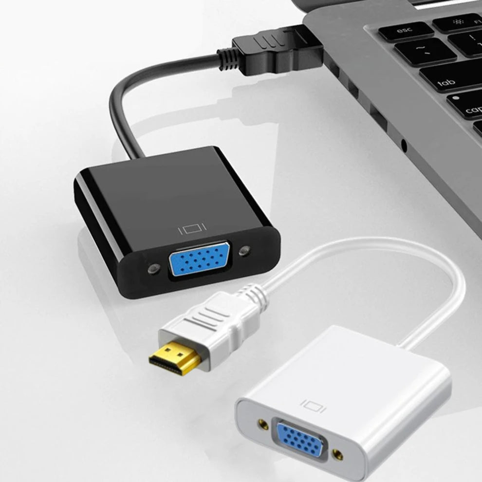 An HDMI to VGA adapter cable connects a laptop to a display, featuring a black adapter and white connector.