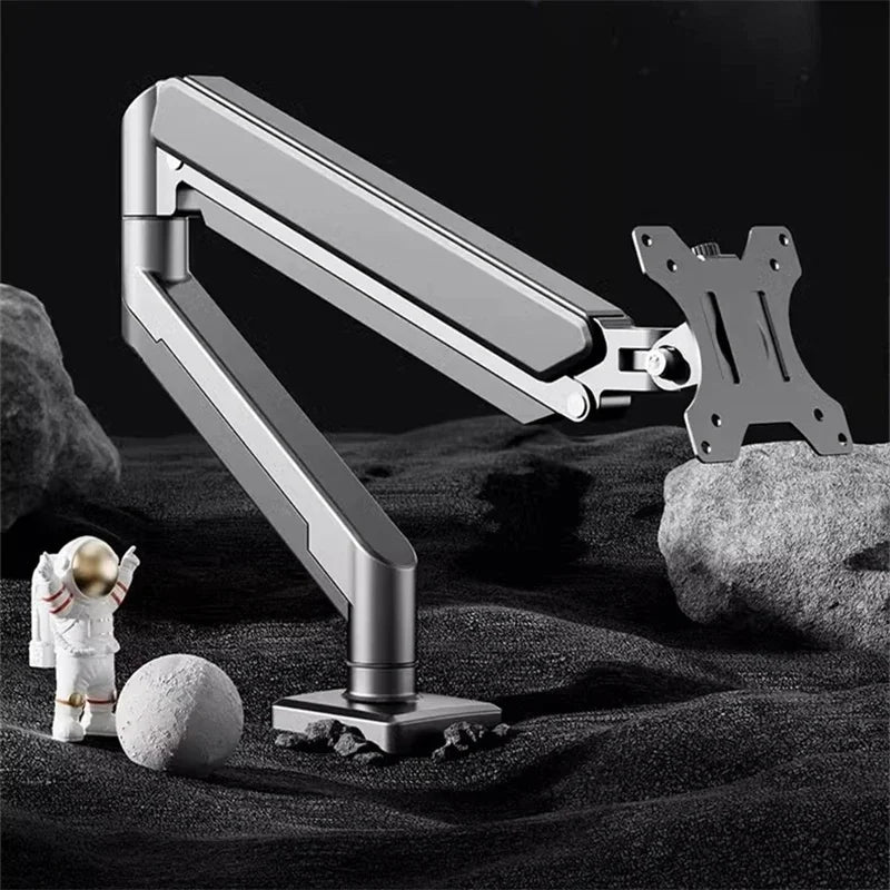A silver adjustable desk monitor arm is shown extending over a dark surface with a small white figure and rocks.