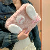 A person holds a pink fluffy rabbit plush case with white ears and pink accents.