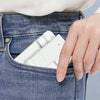 A hand places a white adjustable desktop phone stand into the pocket of blue denim jeans.