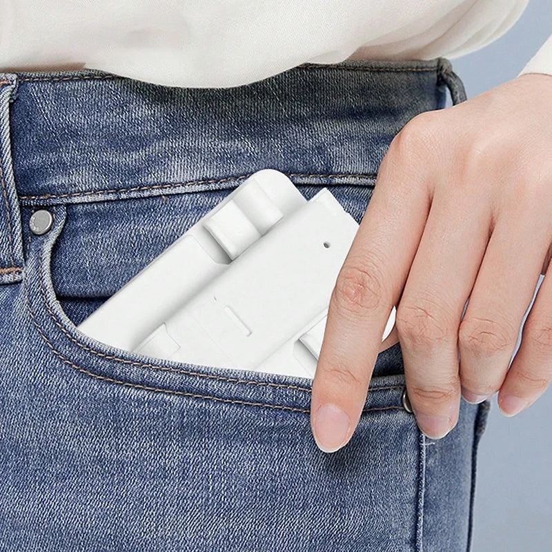 A hand places a white adjustable desktop phone stand into the pocket of blue denim jeans.