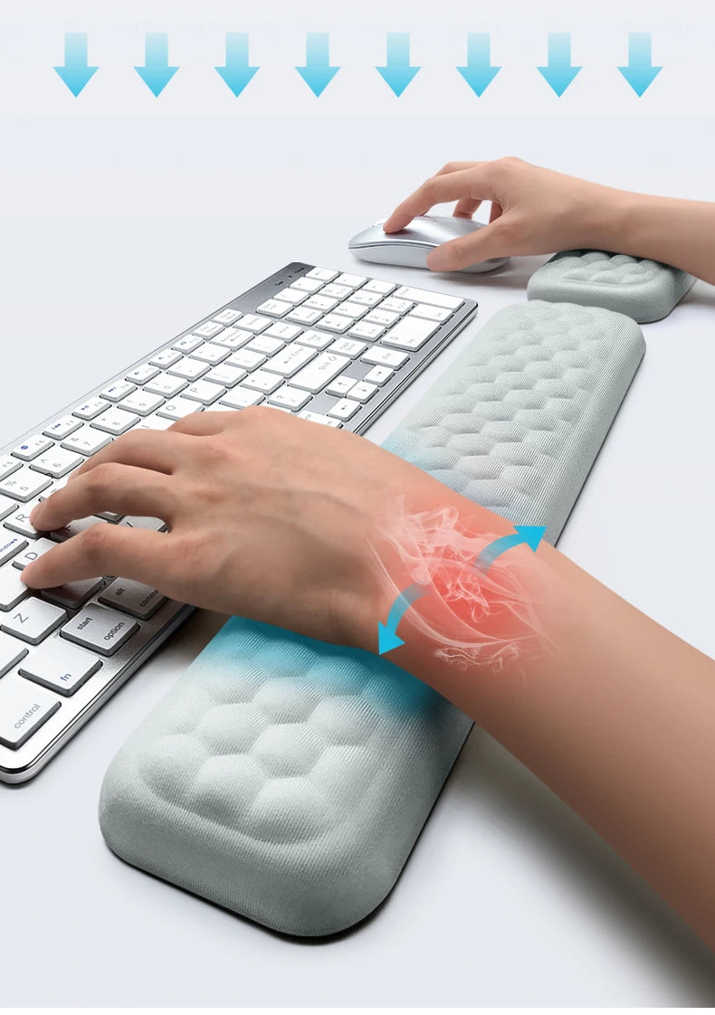A hand rests on an ergonomic keyboard and mouse with a soft wrist rest pad for comfort.