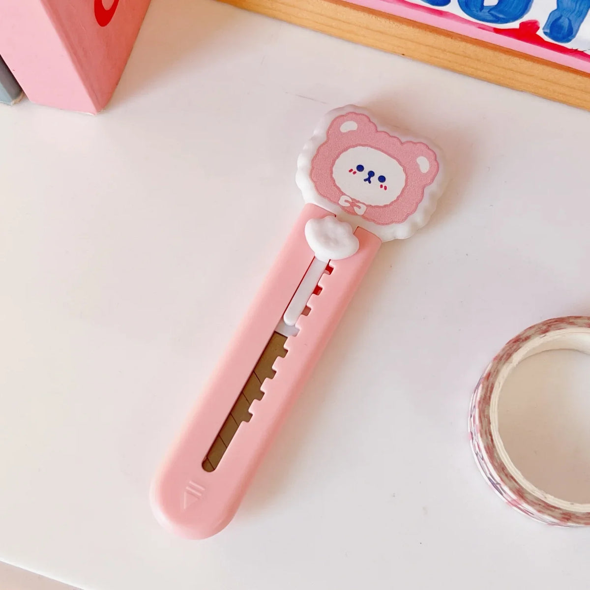 A pink cat paw mini cutter with a round head and a straight blade is shown on a white surface.