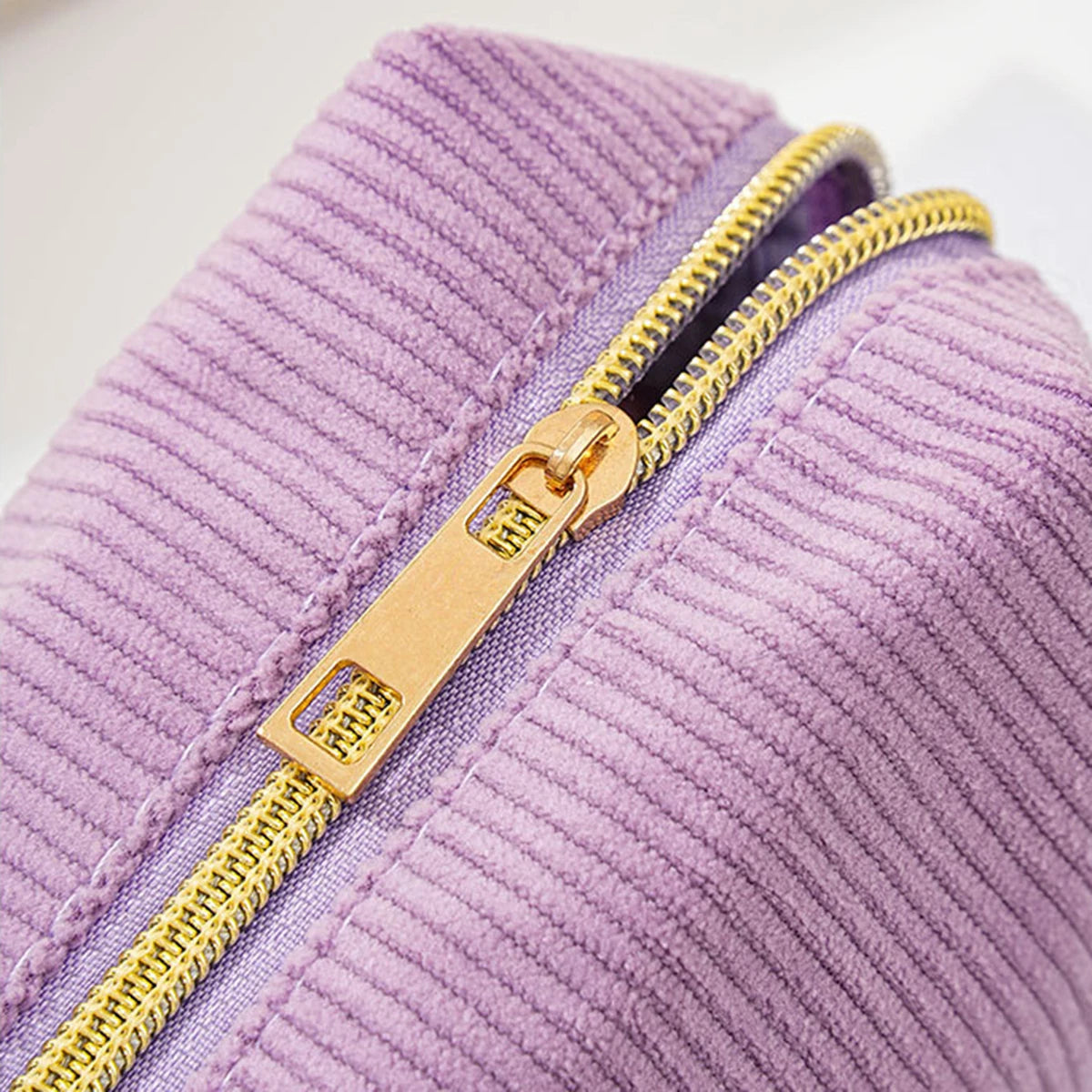 A close-up of a purple striped pencil case with a gold zipper detail.