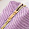 A close-up of a purple striped pencil case with a gold zipper detail.