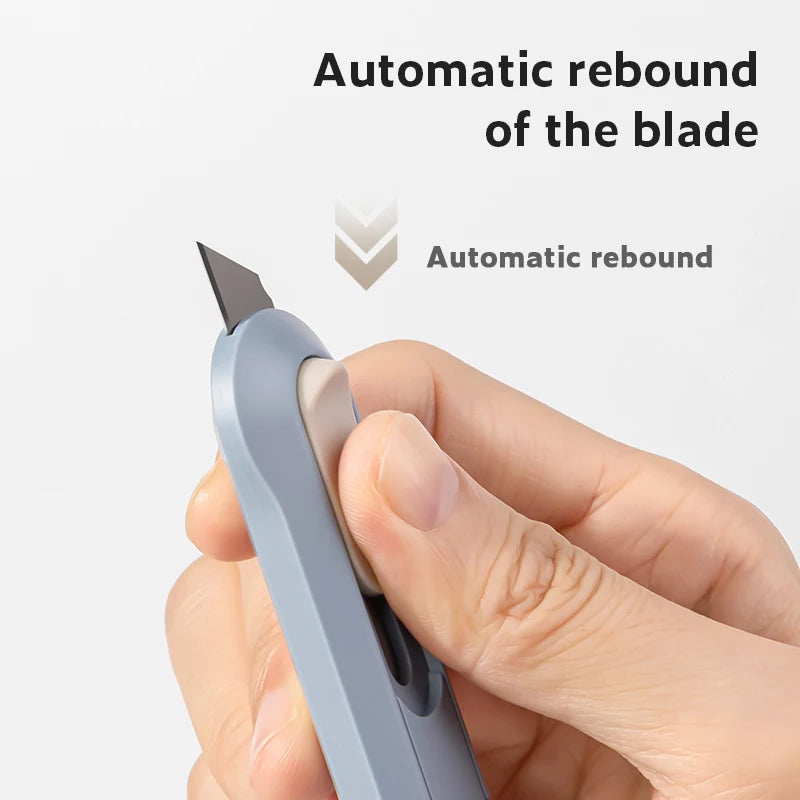 A hand is holding a light blue portable mini paper cutter with an automatic rebound blade.