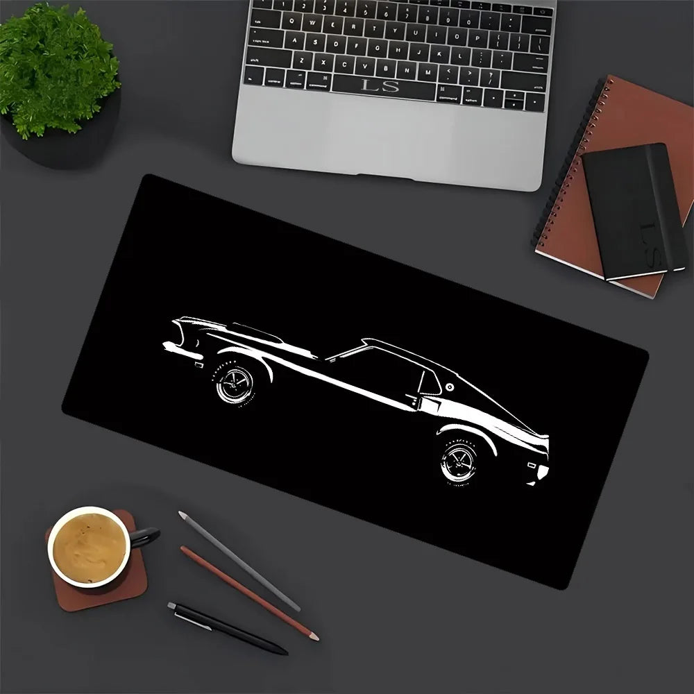 A black silhouette of a JDM sports car is printed on a large black gaming mouse pad with office supplies nearby.
