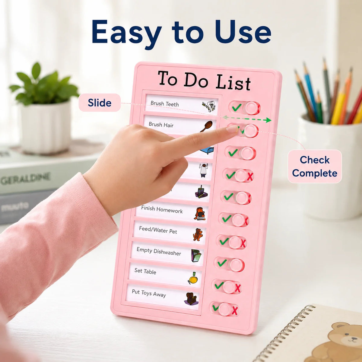 A hand slides a pink reusable to do list board showing various chores and habits like brush teeth and feed a pet.