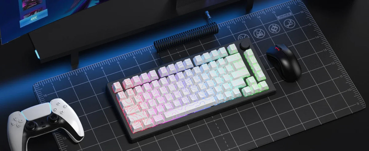 A close-up view of a mechanical keyboard, keycaps, mouse, and controller laid out on a dark surface with a blue grid backgrou
