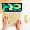 Hands are using a yellow Universal Keyboard Case for an iPad, featuring a colorful graphic design and a wireless mouse.