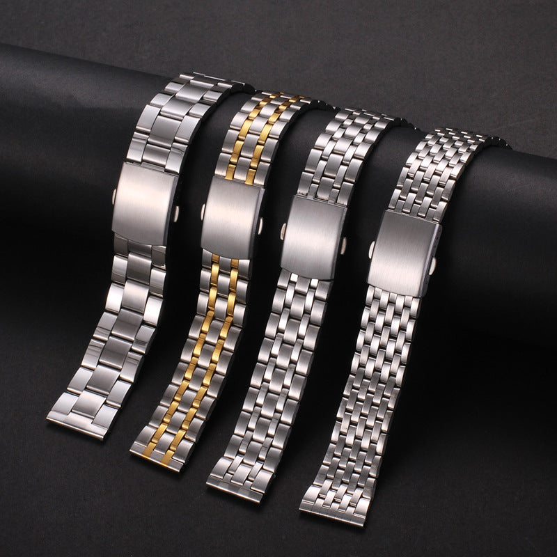 Five stainless steel watch bands with gold accents displayed on a dark surface.