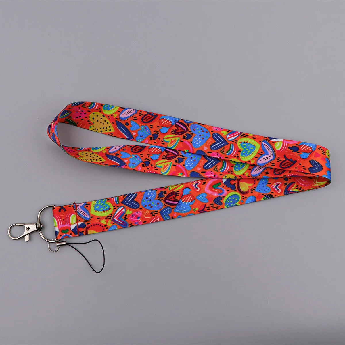 A colorful, heart-shaped lanyard with an orange and pink floral pattern, featuring a metal clip for badges or keys.