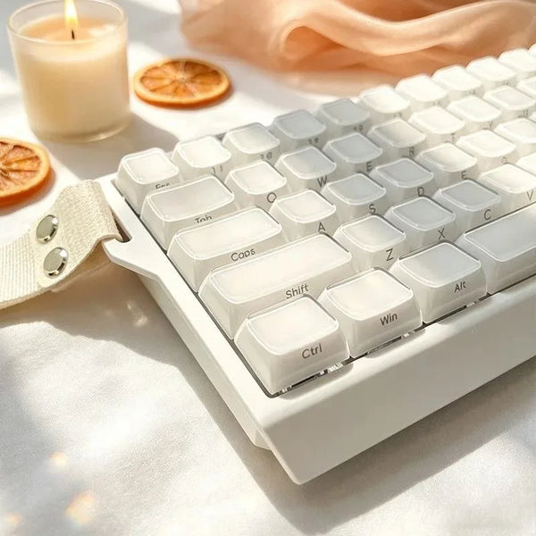 A close-up of white crystal jelly side-printed keycaps for a mechanical keyboard resting on a light surface.