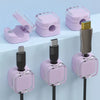 Pink magnetic cable management clips with various connectors mounted on a wall or desk.