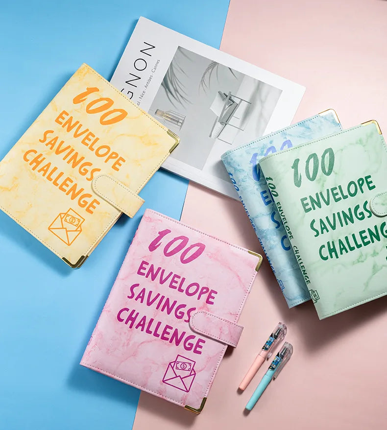 A set of pink and green marble budget binders with envelopes for savings challenges displayed on a pastel background.