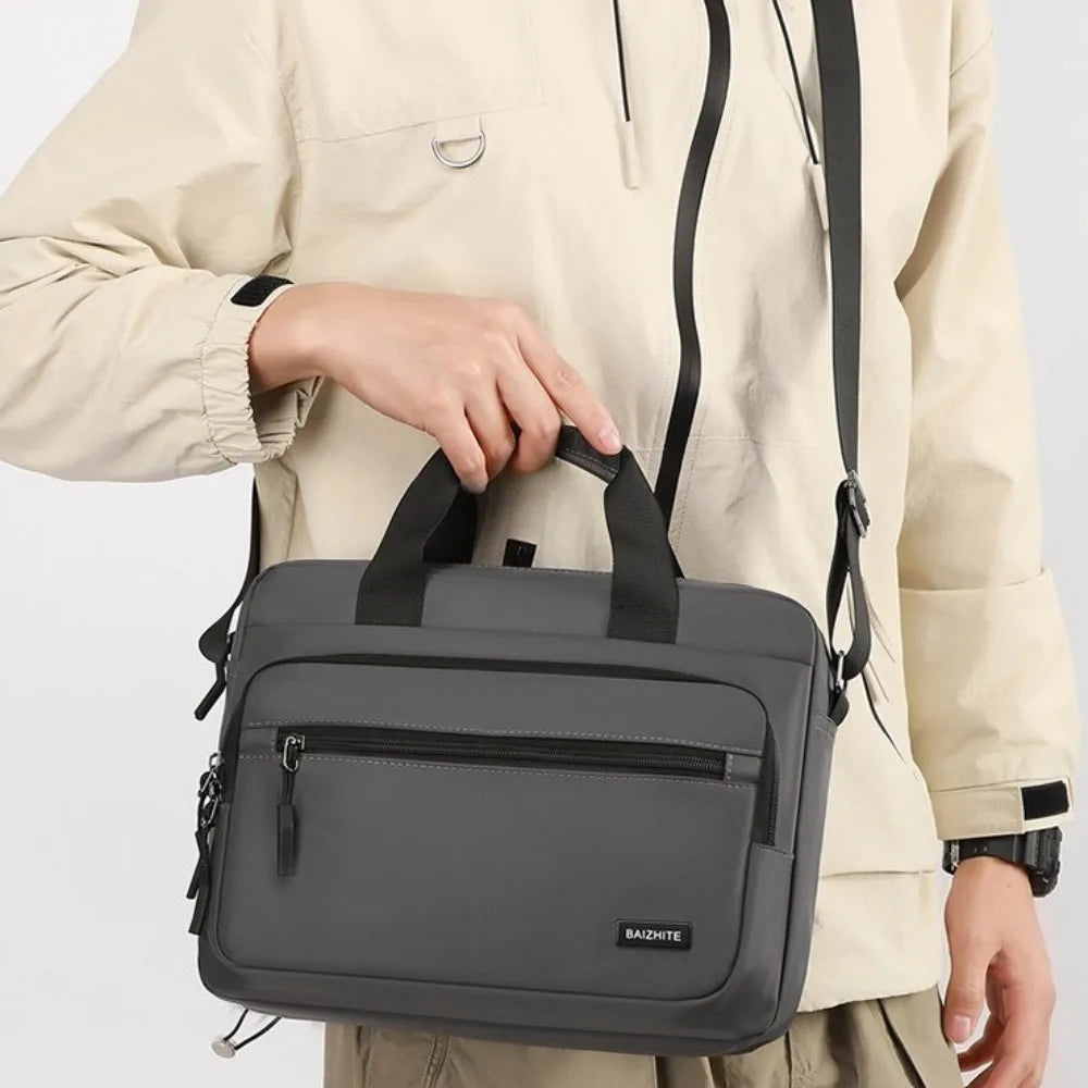 A gray Oxford cloth crossbody briefcase with a laptop compartment is shown being held by a person.