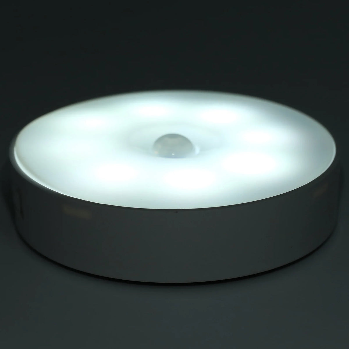 A round, white LED night light with a sensor, designed for cabinet or wardrobe lighting.