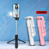 A white selfie stick tripod with a fill light and wireless remote is shown next to two pink and white camera grips.