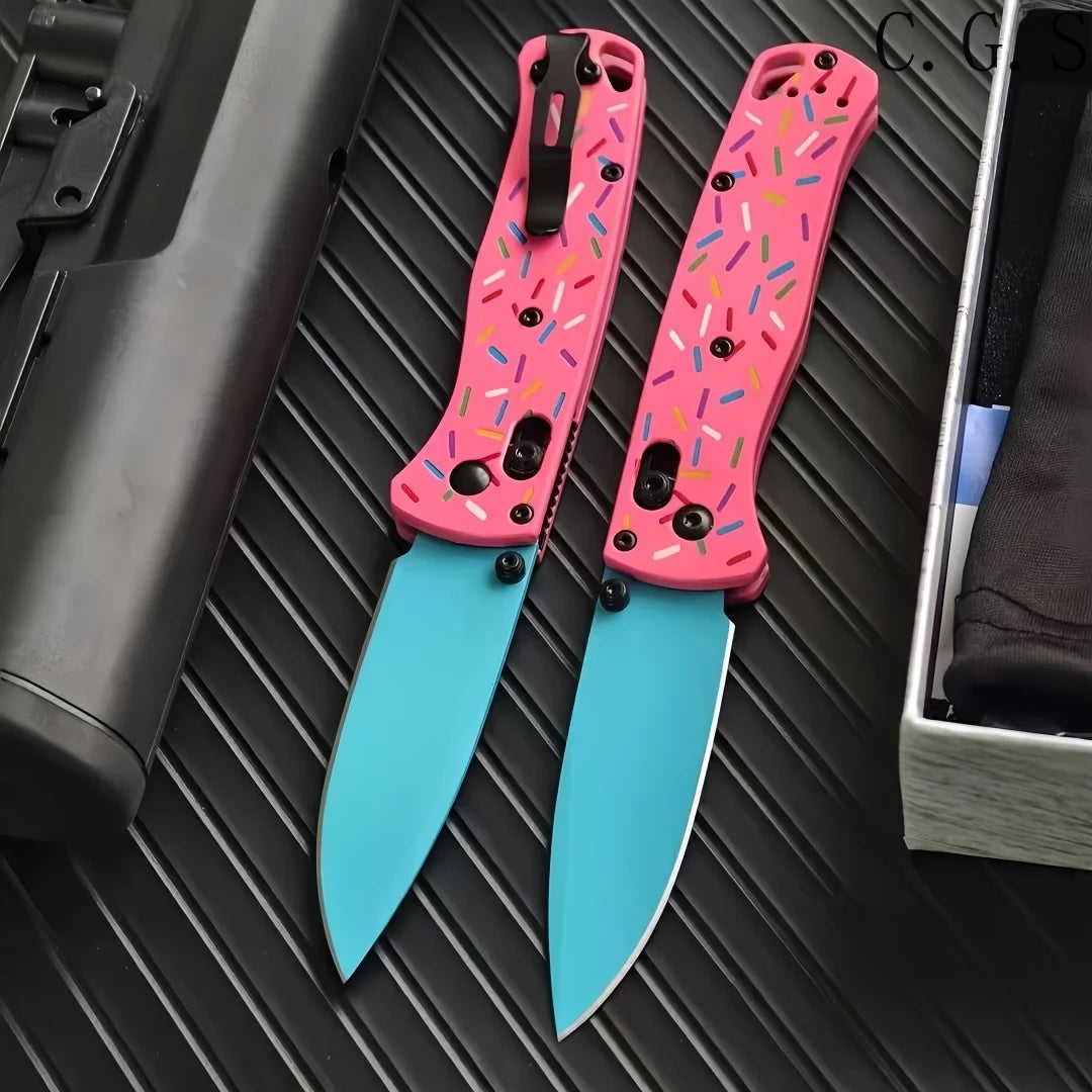 A pair of pink acrylic folding knives with colorful inserts and D2 steel blades resting on a dark surface.