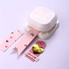 A white crafting tool set featuring a punch corner rounder and various tags with hearts and other designs.